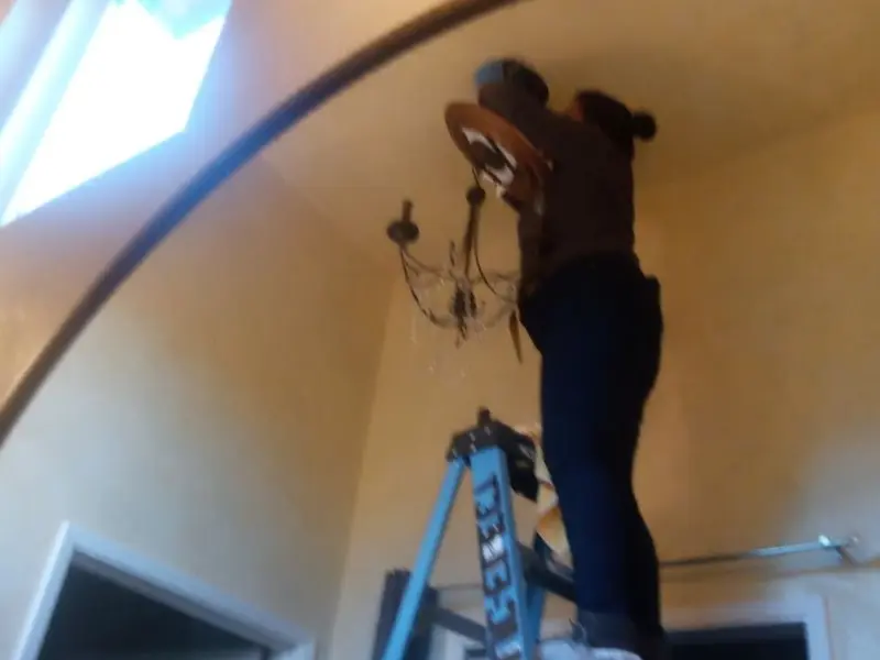 Electrician installing a chandelier in a Linden residence